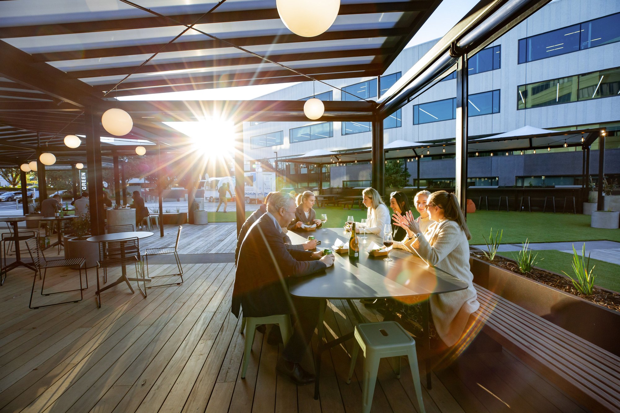 The-Green_Why-Come_Perfect-for-Groups-and-Events Groups dining together on The Green's covered deck at sunset